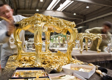 Мастер фабрики Creazioni покрывает столик золотой поталью